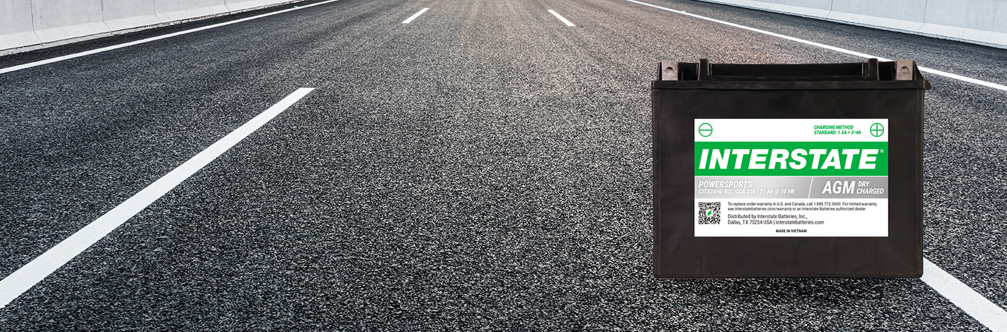 Interstate AGM powersports battery on open paved highway with lane markings stretching into the distance