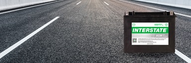Interstate AGM powersports battery on open paved highway with lane markings stretching into the distance