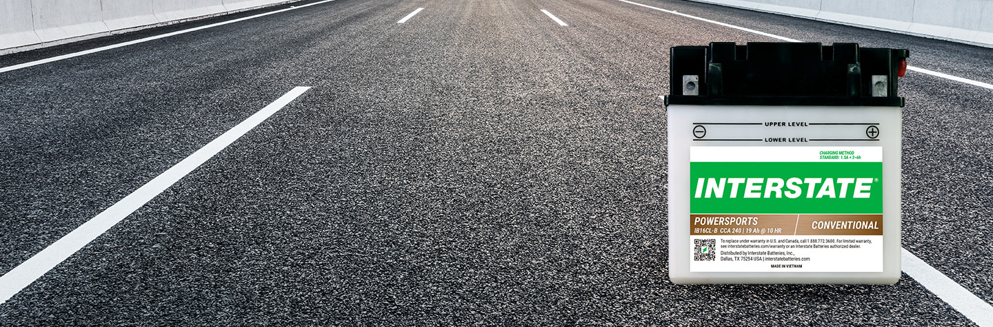 Interstate conventional powersports battery on open paved highway with lane markings stretching into the distance