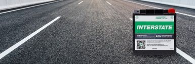 Interstate factory-activated AGM powersports battery on open paved highway with lane markings stretching into the distance