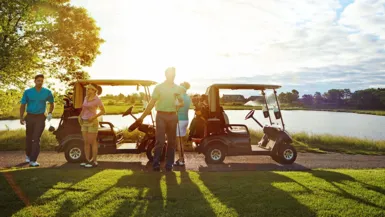 golfers hanging around a golf cart on a golf course