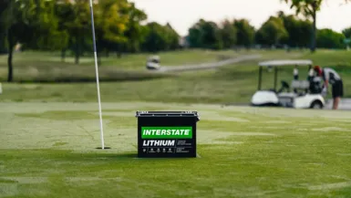 lithium battery on golf course green with golf cart in background