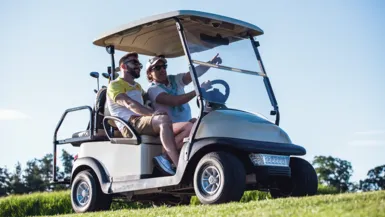 two golfers pointing while riding in a golf cart
